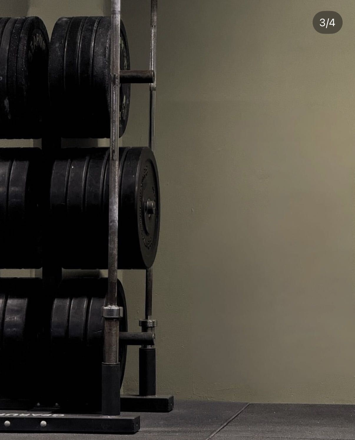 Barbells and bumper plates racked against the olive wall at FIIT Paphos